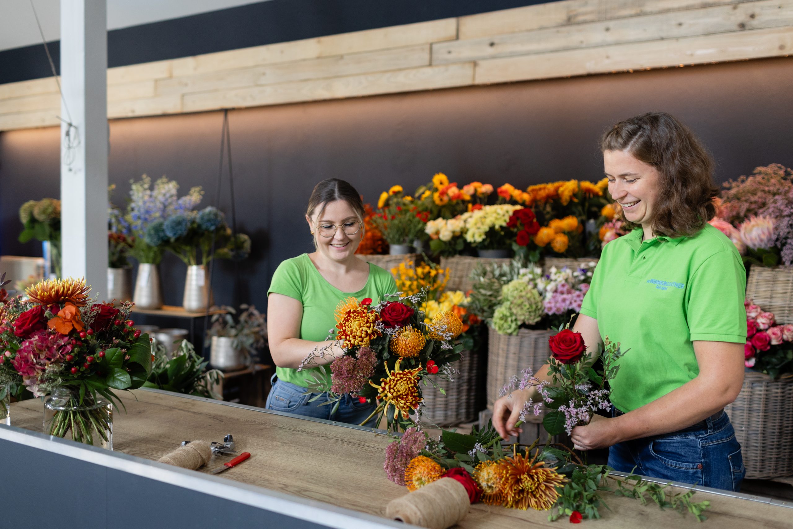 2 Mitarbeiterinnen kreieren bunte Blumengestecke